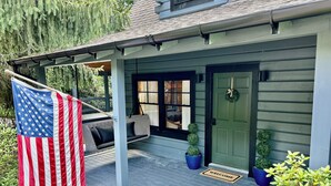 Una casa con porche, una hamaca, un felpudo y una bandera estadounidense.