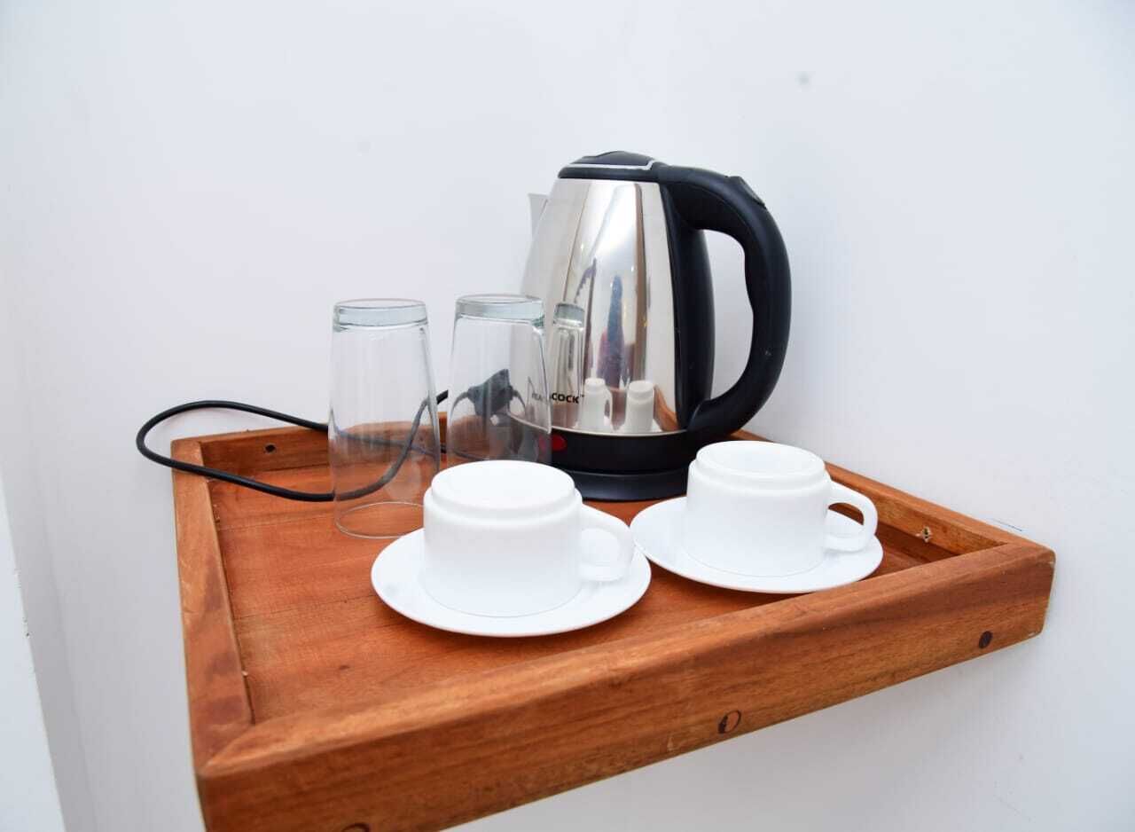 A wooden tray with a kettle, two white cups, and two clear glasses.