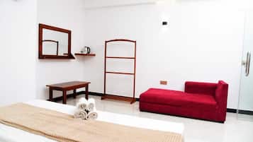 Une chambre d’hôtel avec un lit, un canapé rouge, une étagère en bois avec une bouilloire, une échelle en bois et un miroir au mur.