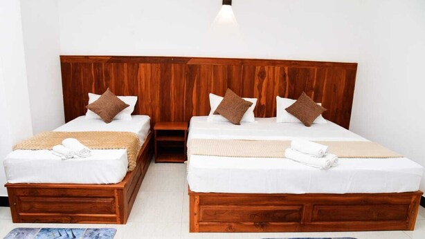 Ein Doppelzimmer mit zwei Betten, jeweils mit einem Holzkopfstück, weißer Bettwäsche und braunen Kissen.