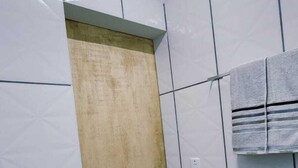 Een badkamer met witte betegelde wanden, een houten deur en een handdoek aan de muur.