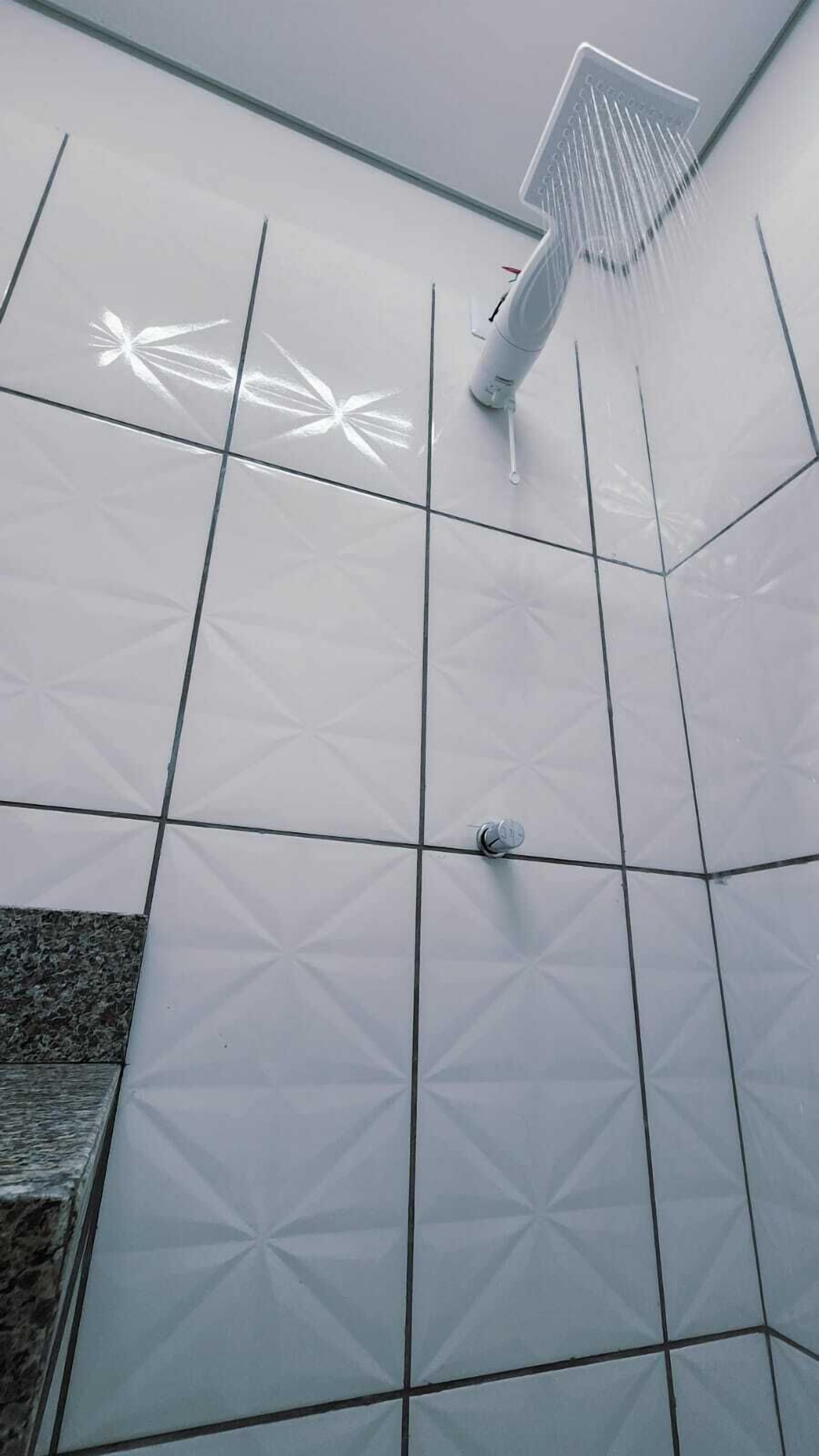 Un espacio de ducha con un estampado geométrico de azulejos y un cabezal de ducha de mano.