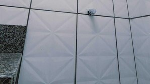 Een douchegedeelte met een geometrisch tegelpatroon en een handdouche.