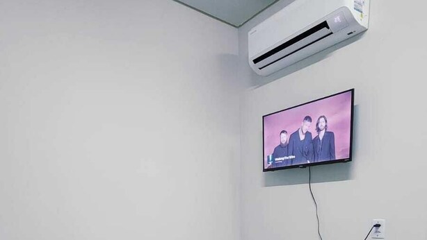 Ein Schlafzimmer mit einem Bett, einer Klimaanlage und einem an der Wand befestigten Fernseher.