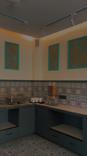 A kitchen with a blue countertop, patterned backsplash, and three framed decorative panels. - StayBird - Azure Suites Business Hotel (Pune)