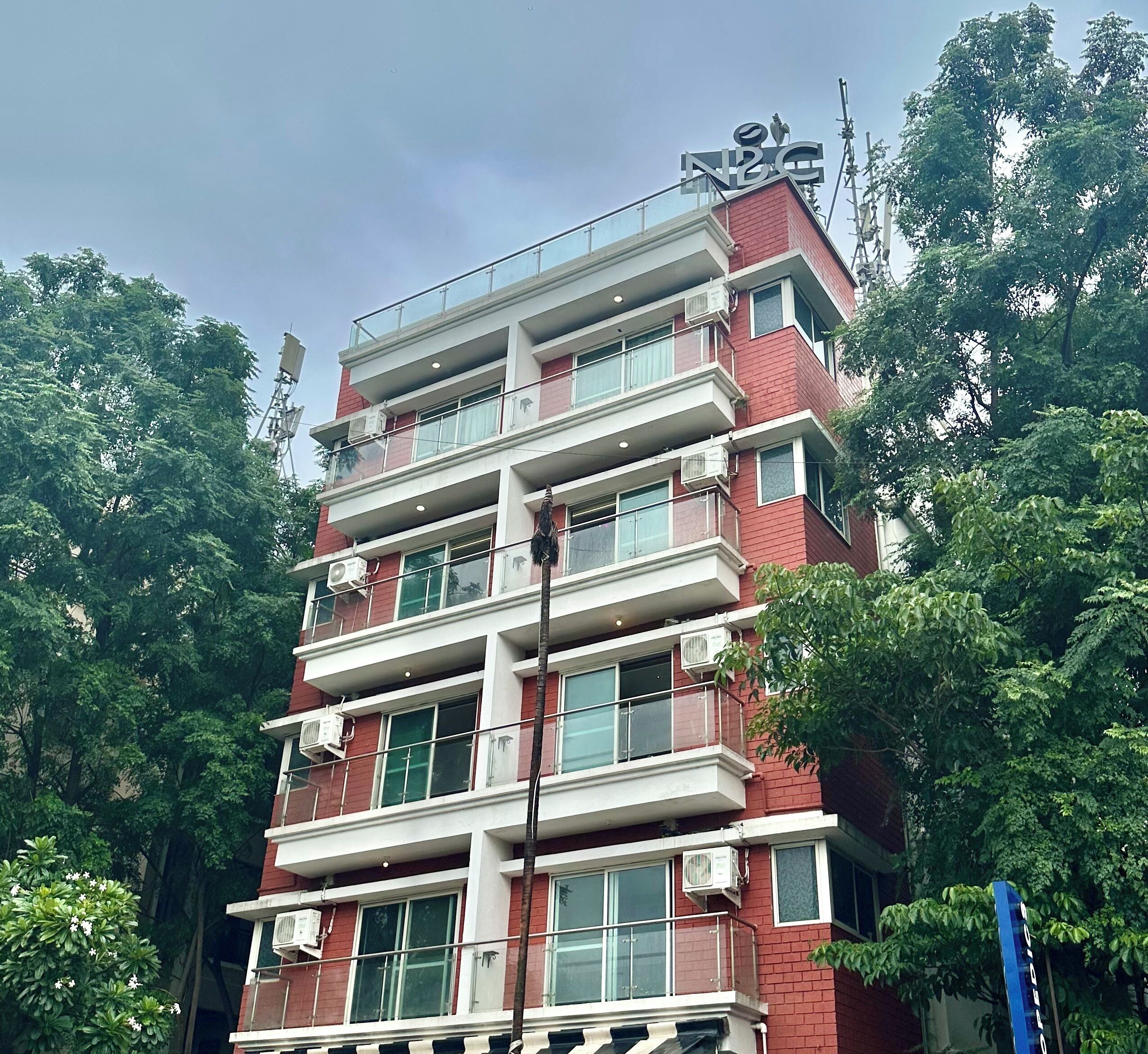 Un edificio de varios pisos con fachada de ladrillo rojo, varios balcones y unidades de aire acondicionado.