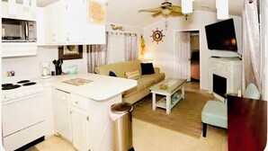 A compact living space with a kitchenette, a sofa, a coffee table, and a television.