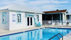 A swimming pool with a wooden deck and lounge chairs.