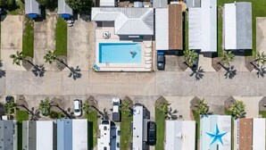 An aerial view of a residential area with multiple mobile homes, a swimming pool, and a few vehicles.