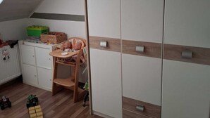 A child's room with a bunk bed, a wardrobe, a small table with toys, and a wooden floor. - Large, cozy and family-friendly vacation apartment with balcony and garden (Bischbrunn)