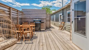 Une terrasse en bois équipée d’un barbecue, de mobilier d’extérieur et d’un espace salon abrité.
