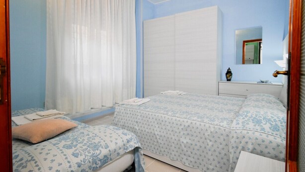 Ein Schlafzimmer mit zwei Betten, einem großen Kleiderschrank, einem Nachttisch und einem Spiegel.