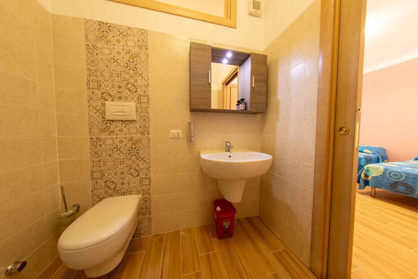 A bathroom with a toilet, sink, and patterned tiles.