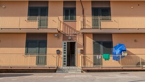 Un immeuble de deux étages doté de balcons, d’une porte et d’un parasol bleu au rez-de-chaussée.