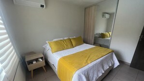 Un dormitorio con cama, mesita de noche y espejo.