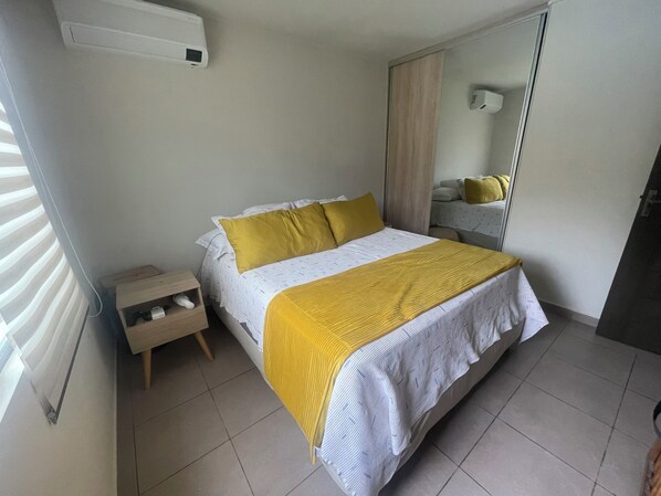 A bedroom with a bed, bedside table, and a mirror.