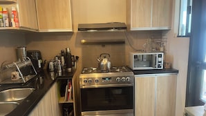 Una cocina compacta con estufa de acero inoxidable, un microondas y armarios de madera.