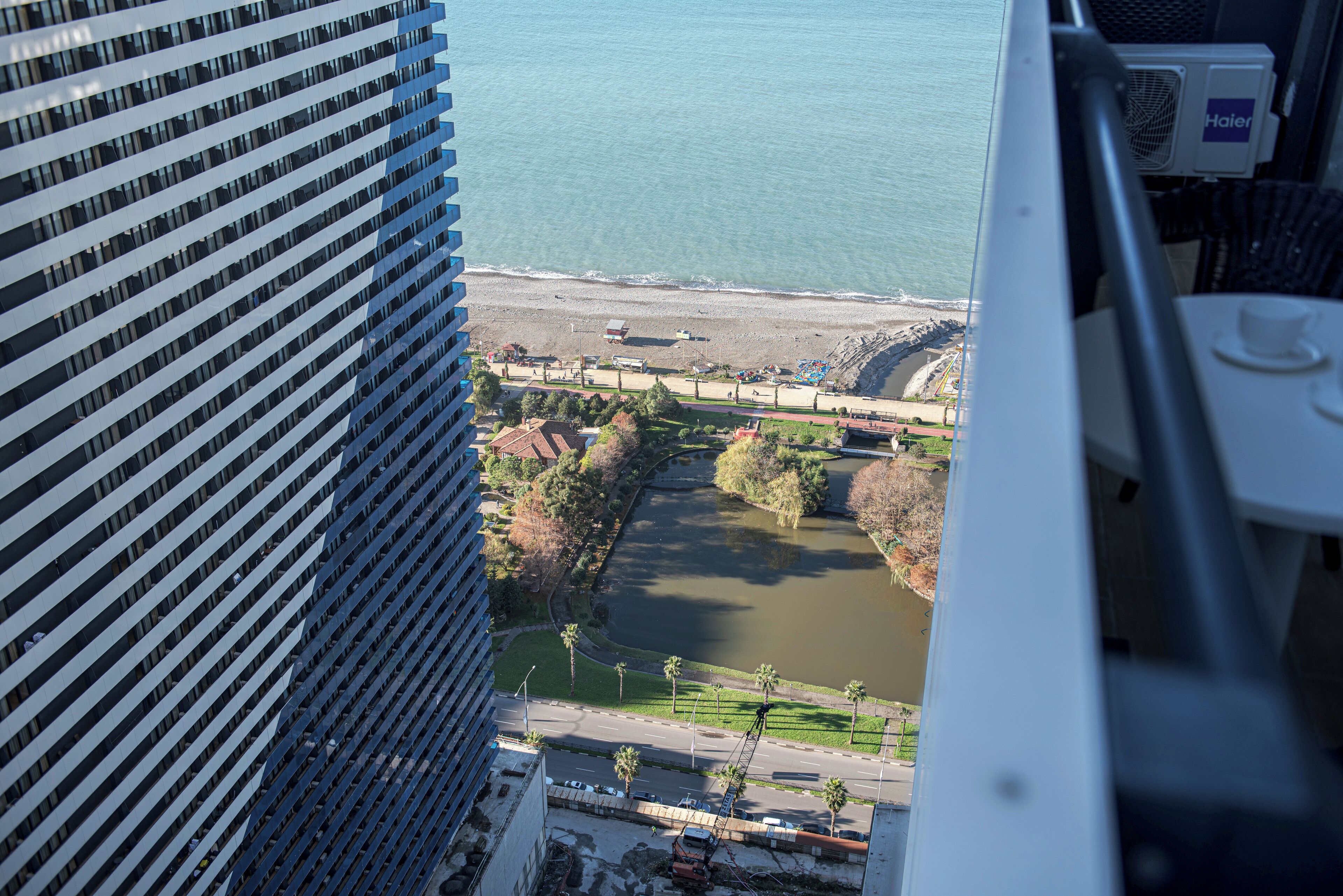 A high-rise building overlooking a beach, a river, and a road with palm trees.