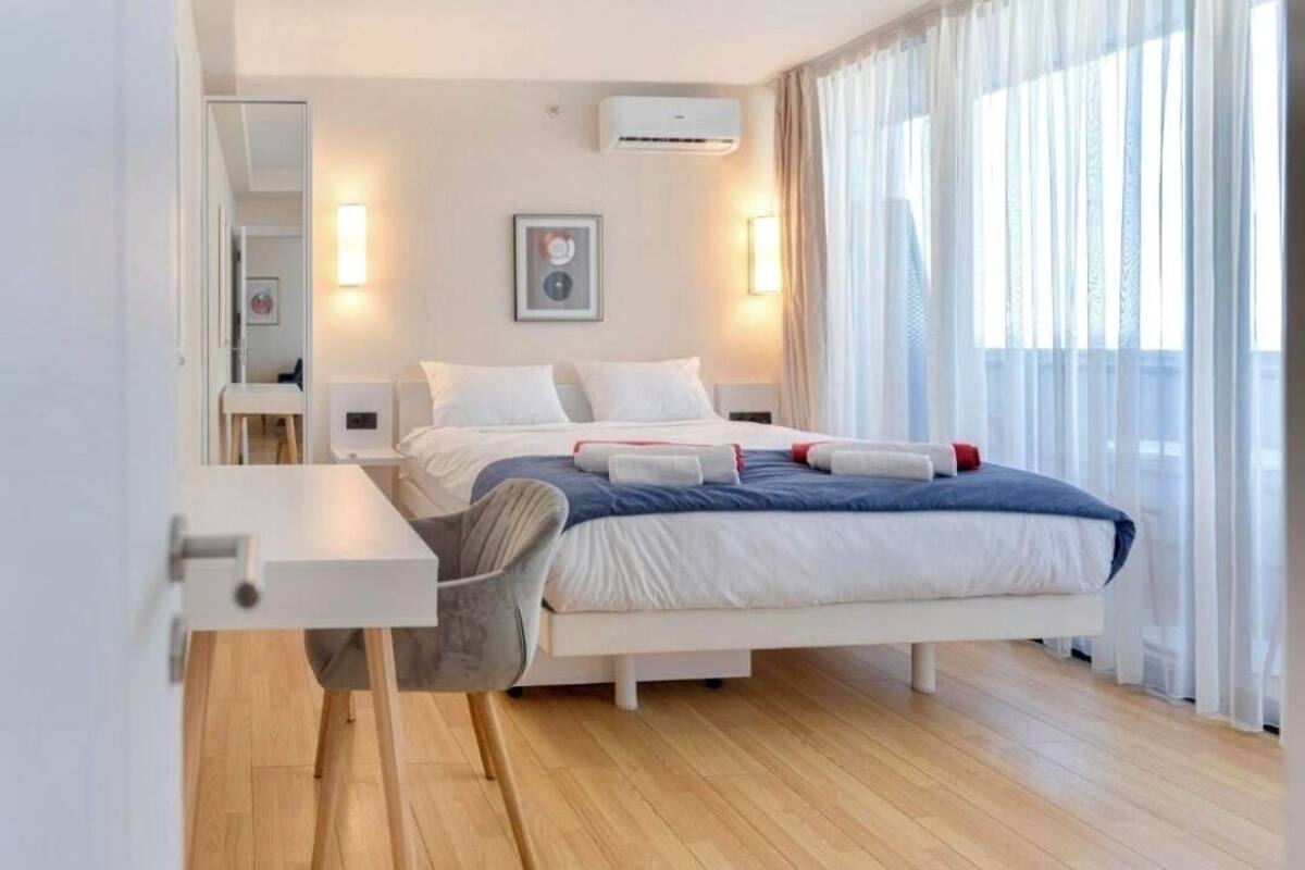 A modern bedroom with a bed, bedside tables, a desk, and a chair.