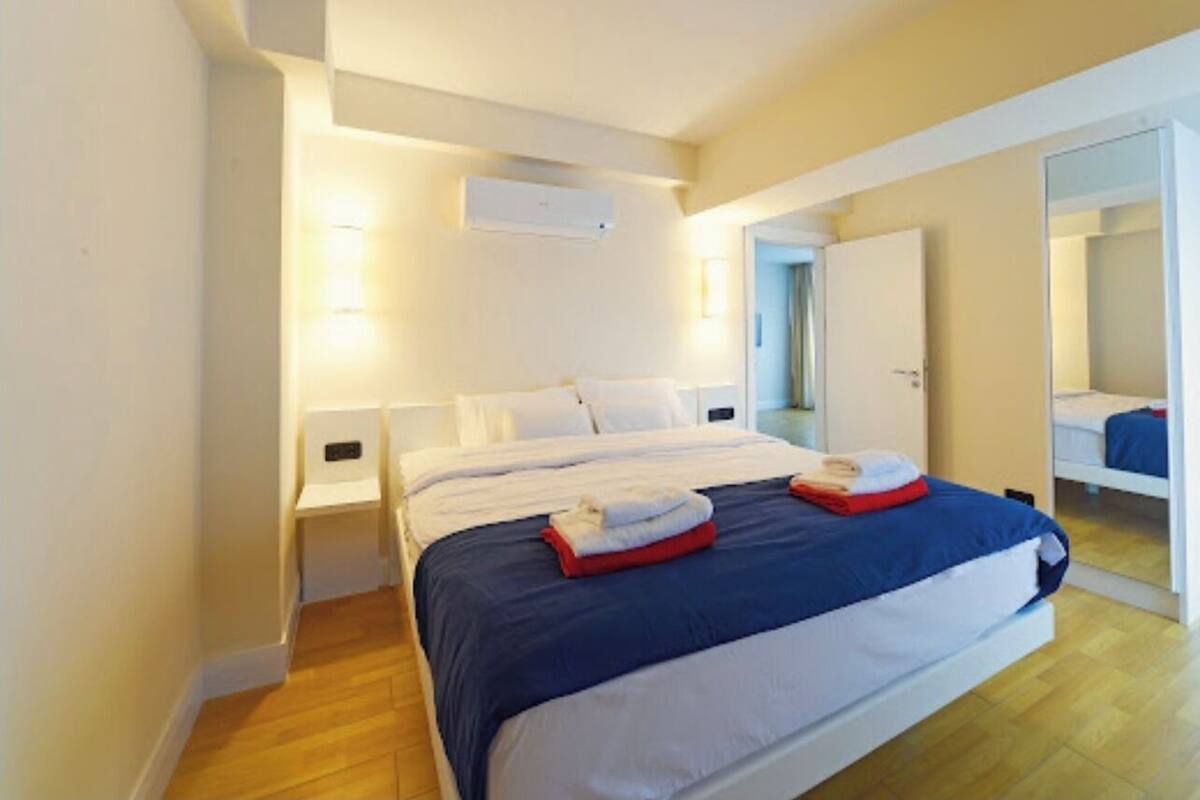 A hotel room with a large bed, a bedside table, a wardrobe, and a mirror.