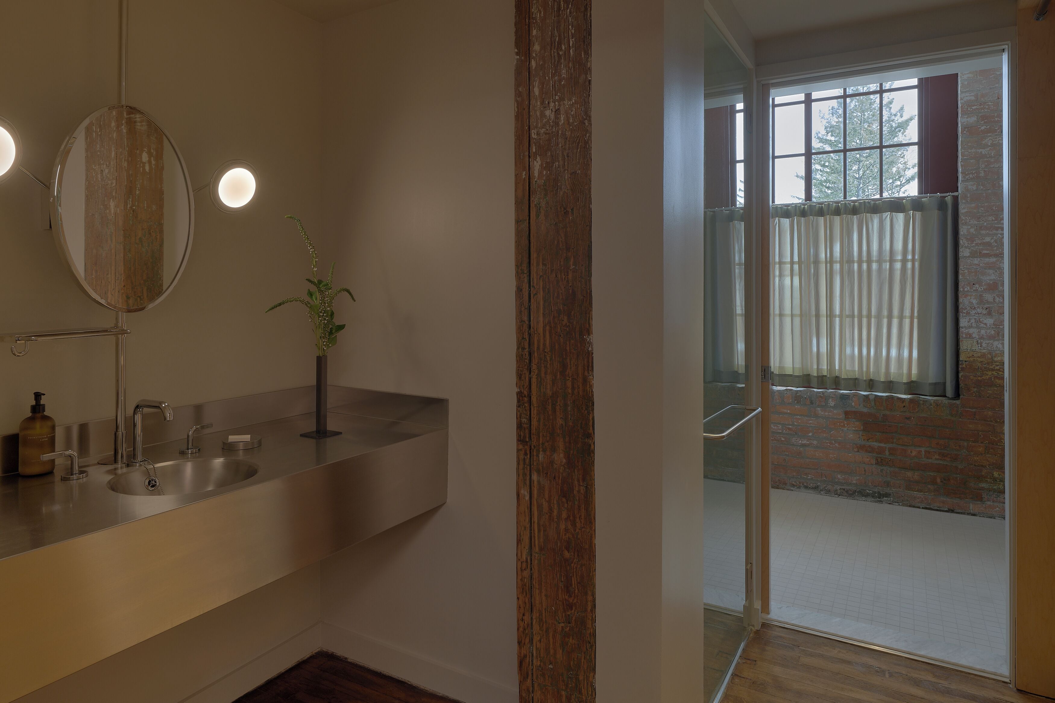 Ein Badezimmer mit einem modernen Waschbecken, einem Spiegel und Blick auf einen Balkon mit einem Fenster.