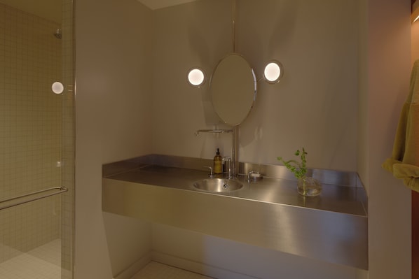 A bathroom with a large mirror, a sink, and a shower. - Pocketbook Hotel and Bath (Hudson)