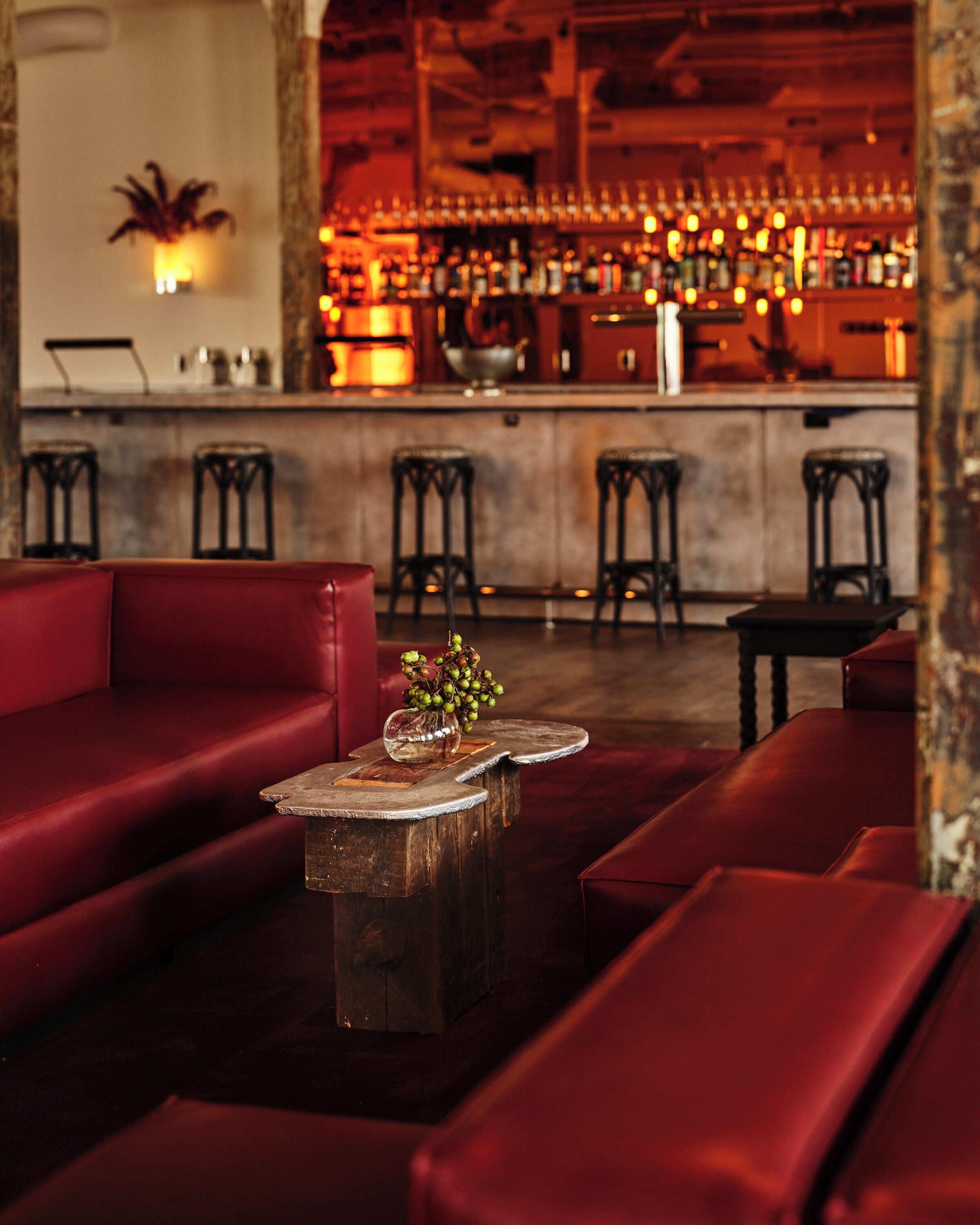 A bar area with a counter, stools, and a red seating area.