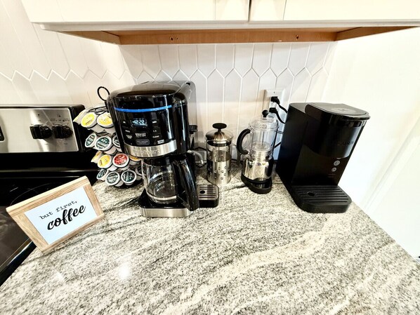 A kitchen counter with a coffee maker, a scale, and a coffee grinder.