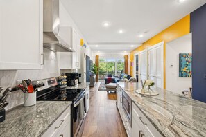 Cocina moderna con encimeras de granito, electrodomésticos de acero inoxidable y vistas a un balcón.
