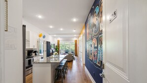 A modern kitchen with a central island, white cabinetry, and a view to the outside.