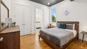 A bedroom with a wooden bed, a nightstand, a dresser, and a large mirror.
