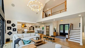 A spacious living area with a high ceiling, a staircase, and a kitchen in the background. - Lakefront Lake Anna, Beach, Dock, Deck Vie (Bumpass)