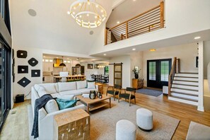 A spacious living area with a high ceiling, a staircase, and a kitchen in the background. - Lakefront Lake Anna, Beach, Dock, Deck Vie (Bumpass)