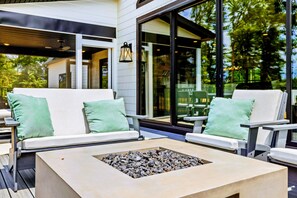 An outdoor seating area with two white chairs and a table with a fire pit.