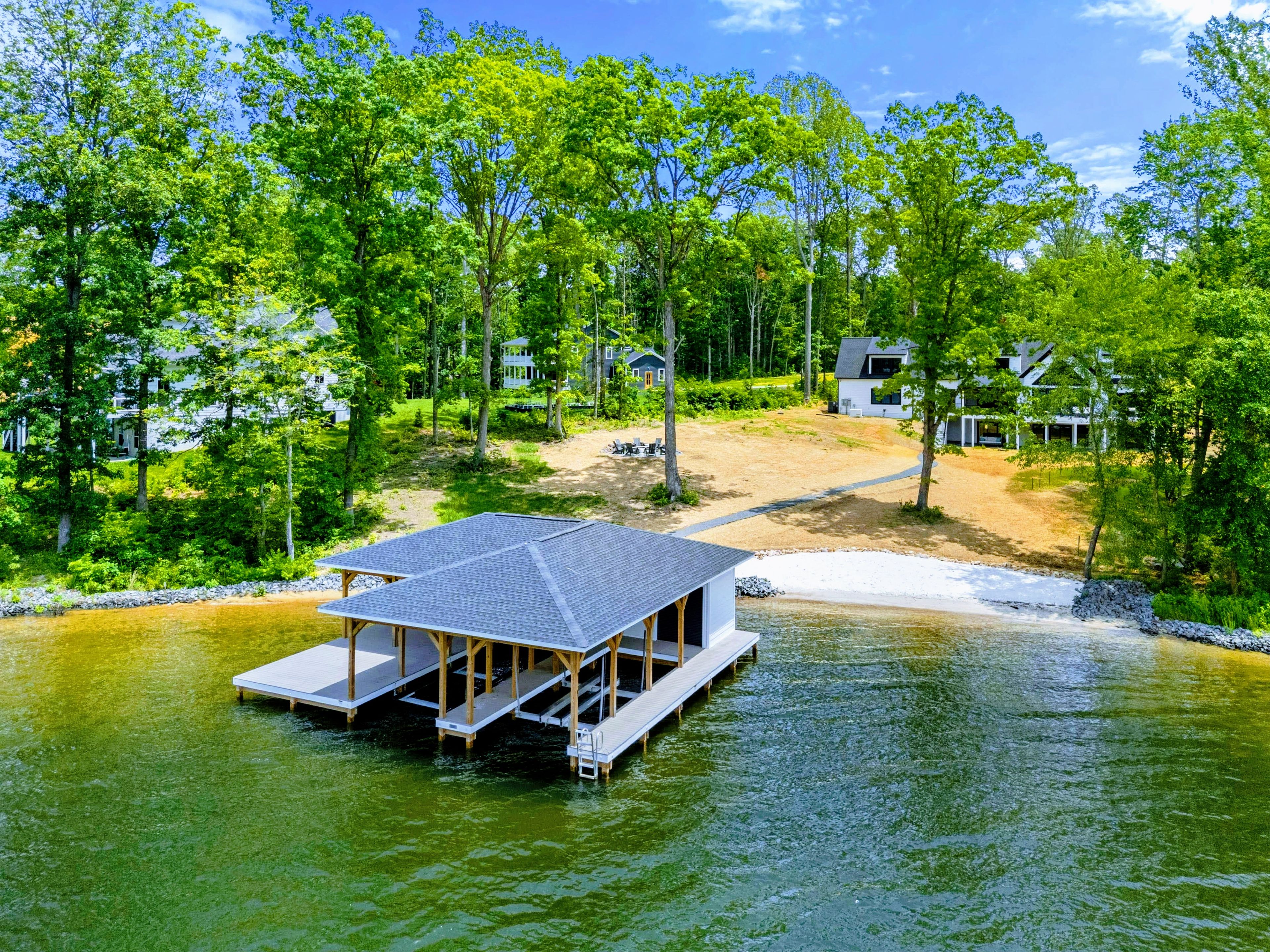 A houseboat with a deck and a covered area, surrounded by trees and a body of water.