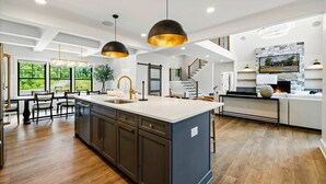 A modern kitchen with a large island, pendant lighting, and a staircase leading to an upper level. - Lakefront Lake Anna, Beach, Dock, Deck Vie (Bumpass)