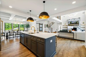 A spacious kitchen with a large island, pendant lighting, and a staircase leading to an upper level. - Lakefront Lake Anna, Beach, Dock, Deck Vie (Bumpass)