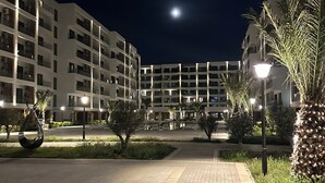 A nighttime view of a multi-story residential building with a paved walkway and street lamps. - Sea Breeze Stylish Studio with Private Terrace (Nardaran)