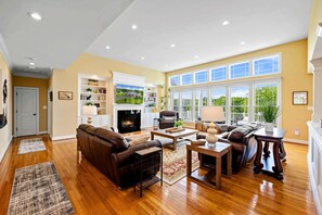A spacious living room with hardwood flooring, a fireplace, a large window, and a cozy seating area. - Lakefront @ Lake Anna, Deck, Boat House, Beach (Mineral)