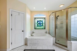 Un bagno con vasca, box doccia in vetro e finestra con vetri colorati.