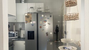 Une cuisine moderne équipée d’appareils électroménagers en acier inoxydable, d’un réfrigérateur orné d’aimants et d’un panier suspendu.