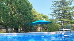 An outdoor swimming pool with a blue mosaic tile pattern, surrounded by trees and a blue umbrella. - La maison aux oiseaux - Luberon (Oppède)