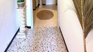 A hallway with a stone column, a potted plant, a decorative rug, and a door leading to another room. - La maison aux oiseaux - Luberon (Oppède)
