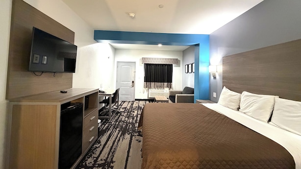 A hotel room with a bed, a desk, a chair, a television, and a bathroom.