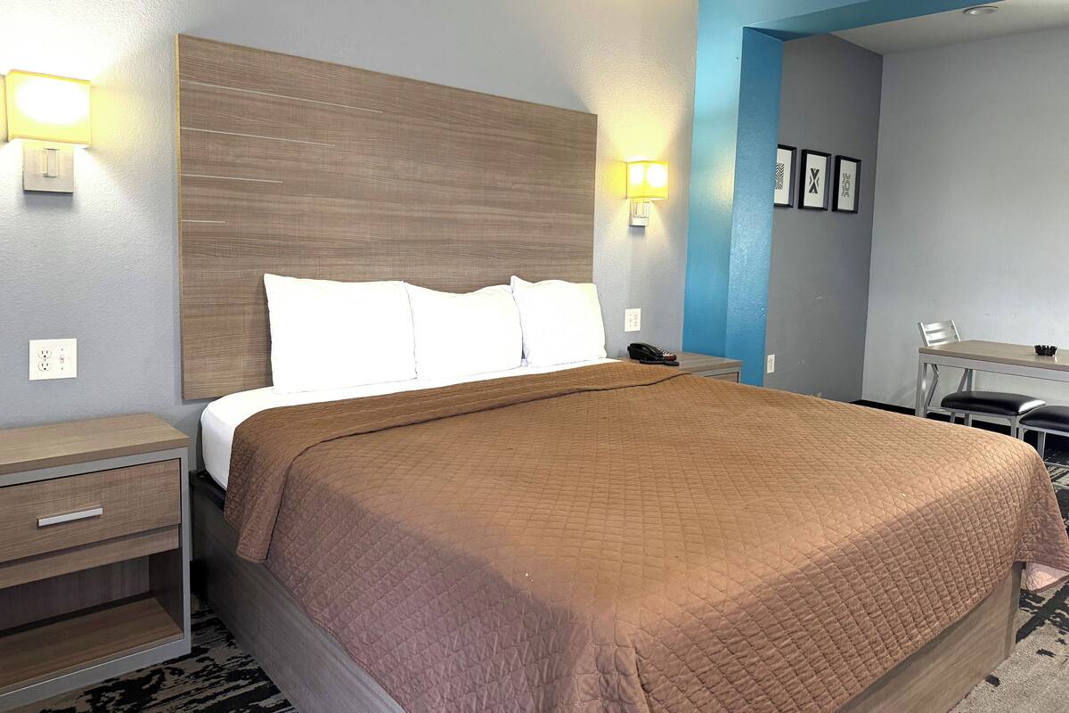 A hotel room with a large bed, bedside tables, a desk, and a chair.