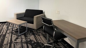 A room with a desk, a chair, a sofa, and a small table.