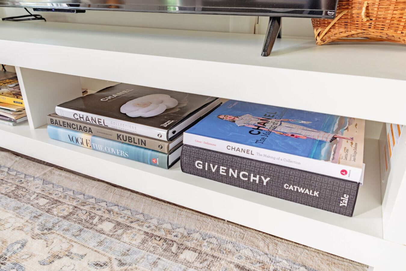 Une bibliothèque contenant des livres, notamment les ouvrages intitulés « CHANEL COLLECTIONS » et « BALENCIAGA ».