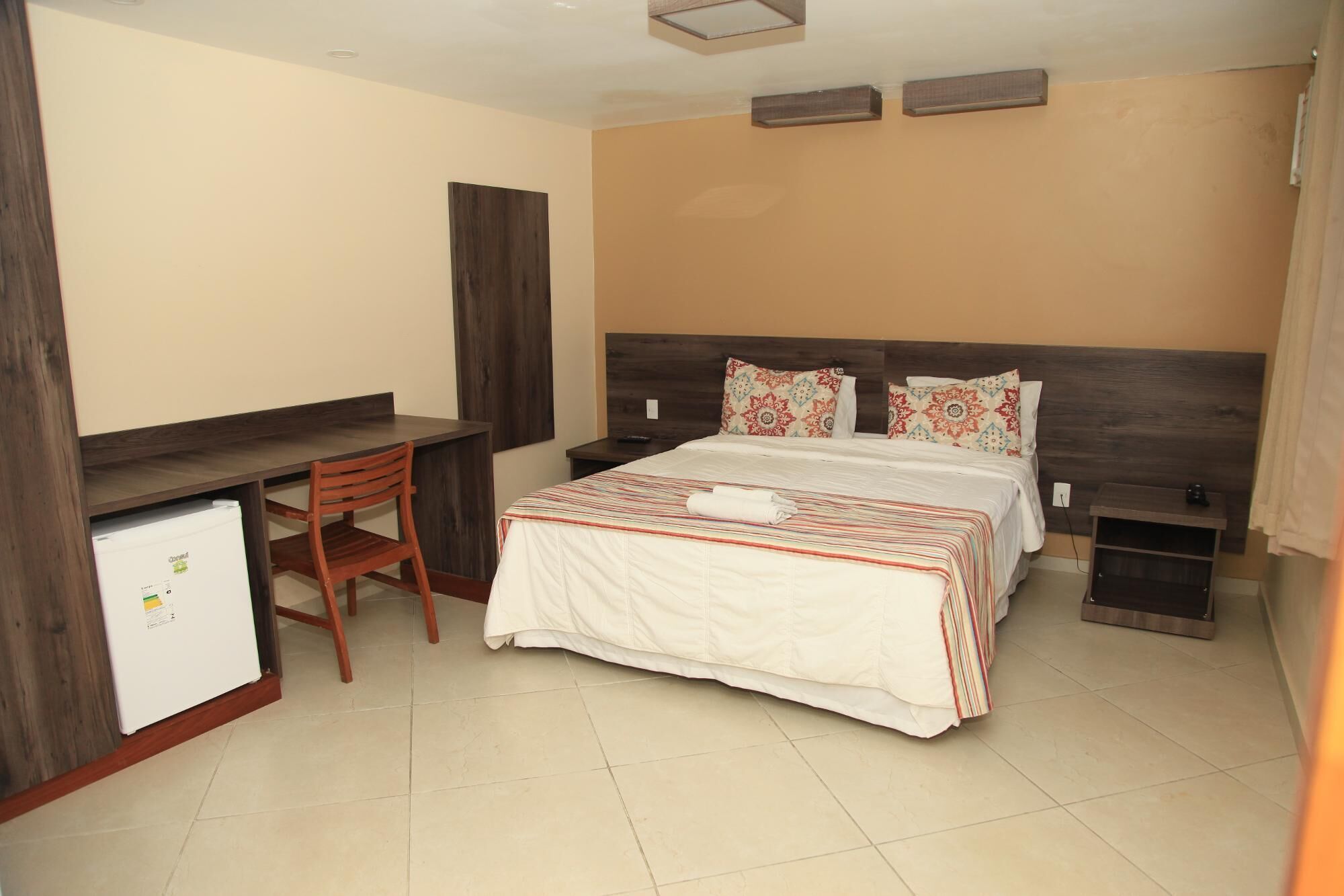 A hotel room with a bed, a desk, and a chair.