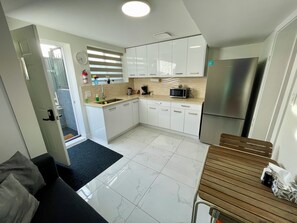 A modern kitchen with white cabinets, a stainless steel refrigerator, and a microwave.