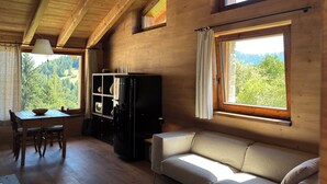 Une pièce chaleureuse avec un plafond en bois, un canapé, un meuble pour la télévision et une table à manger avec des chaises.